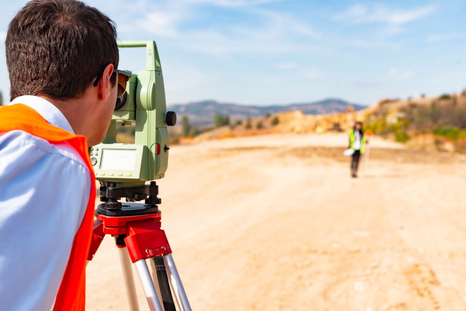Surveyor sighting a property corner through a theodolite